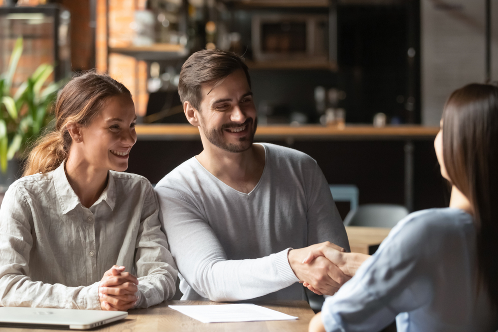 Happy young couple shake hand of bank manager